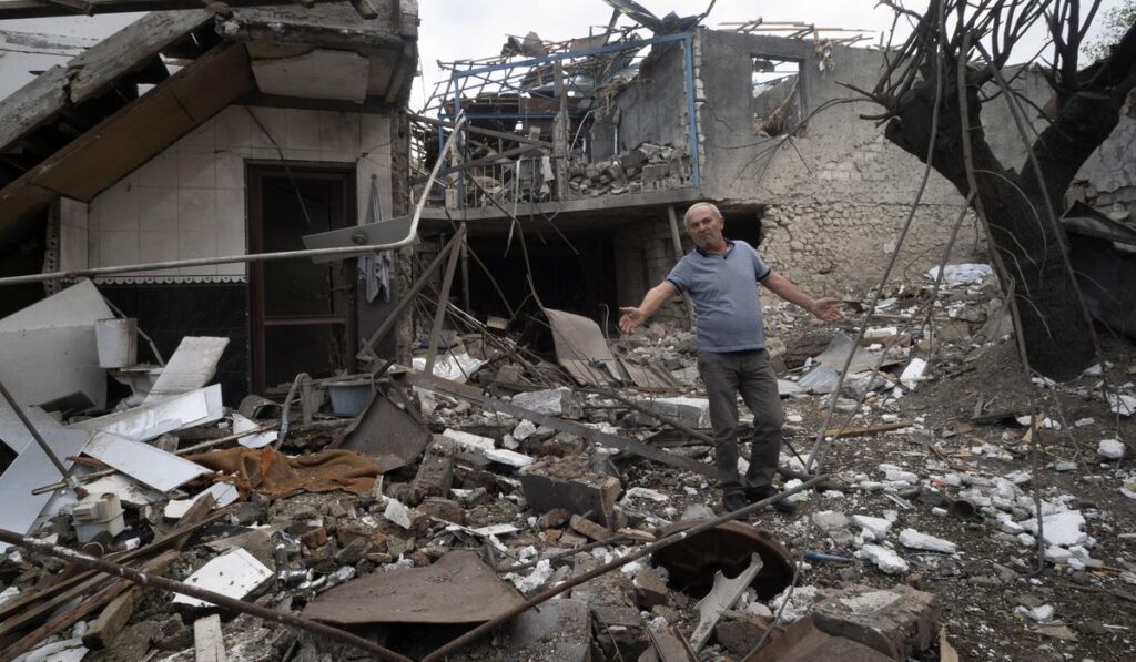 A man gestures in the yard of a house destroyed by shelling by Azerbaijan's artillery during a military conflict in Stepanakert, the separatist region of Nagorno-Karabakh, Friday, Oct. 9, 2020. The latest outburst of fighting between Azerbaijani and Armenian forces began Sept. 27 and marked the biggest escalation of the decades-old conflict over Nagorno-Karabakh. The region lies in Azerbaijan but has been under control of ethnic Armenian forces backed by Armenia since the end of a separatist war in 1994.
