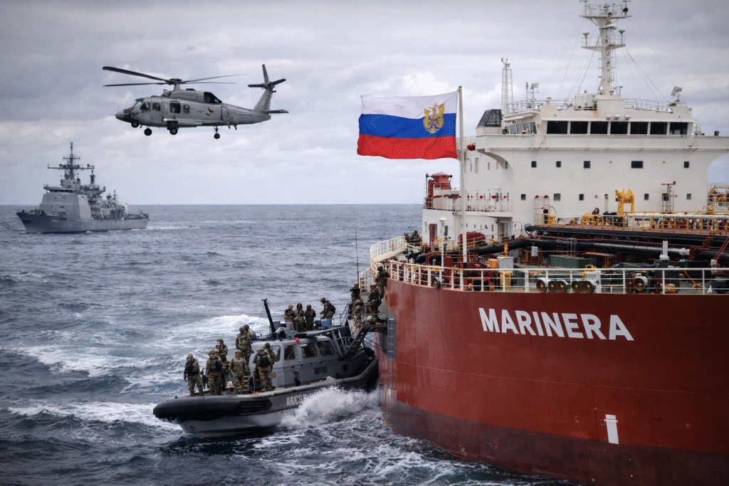 US Coast Guard and military personnel boarding the Russian-flagged oil tanker Marinera in the North Atlantic, with a helicopter and naval vessels visible during a sanctions enforcement operation.