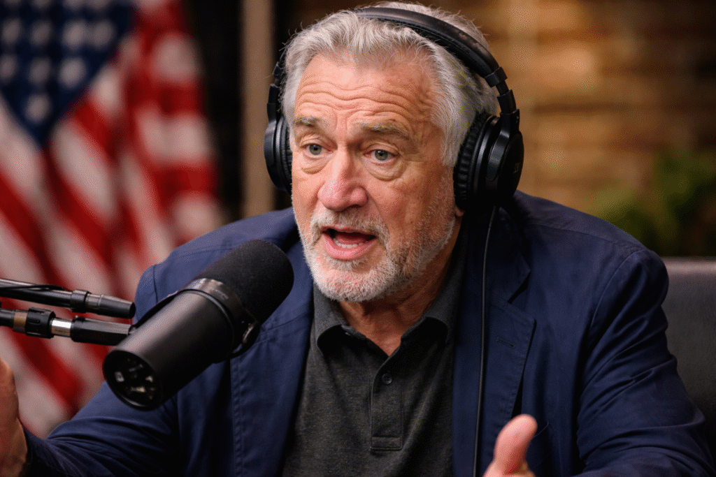 Robert De Niro speaking into a microphone during a political podcast discussion.