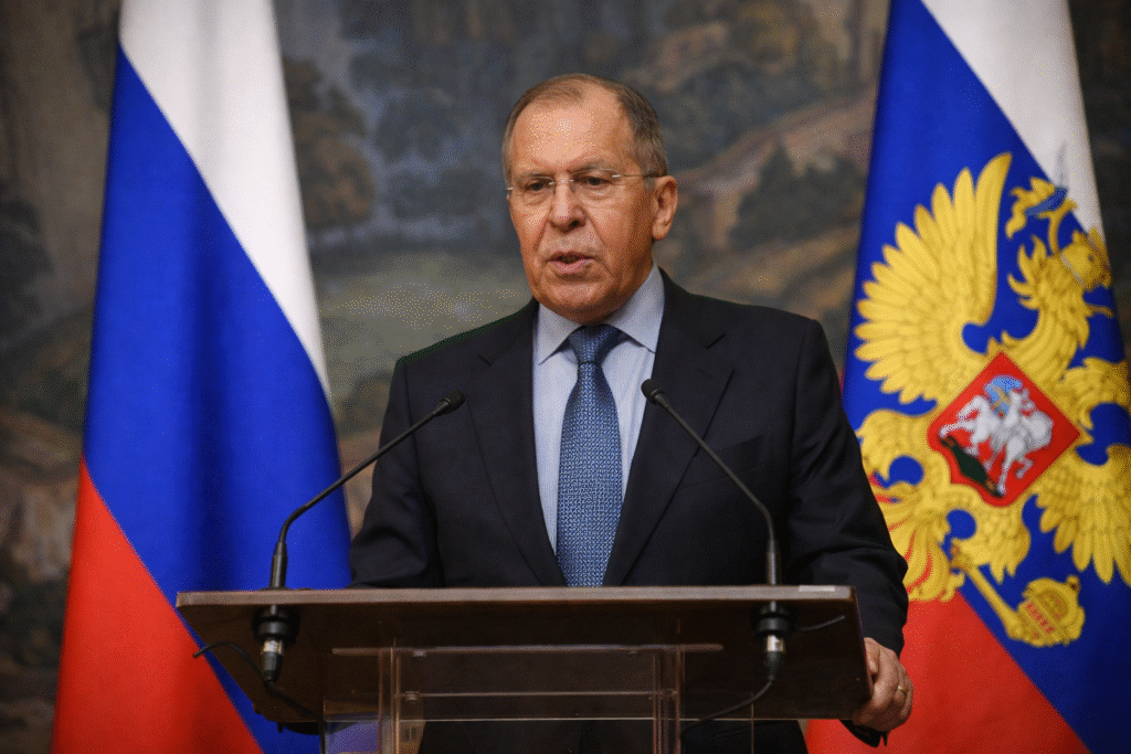Russian Foreign Minister Sergei Lavrov speaking at a press conference in Moscow with flags in the background, illustrating Russia’s foreign policy stance against threats and blackmail.
