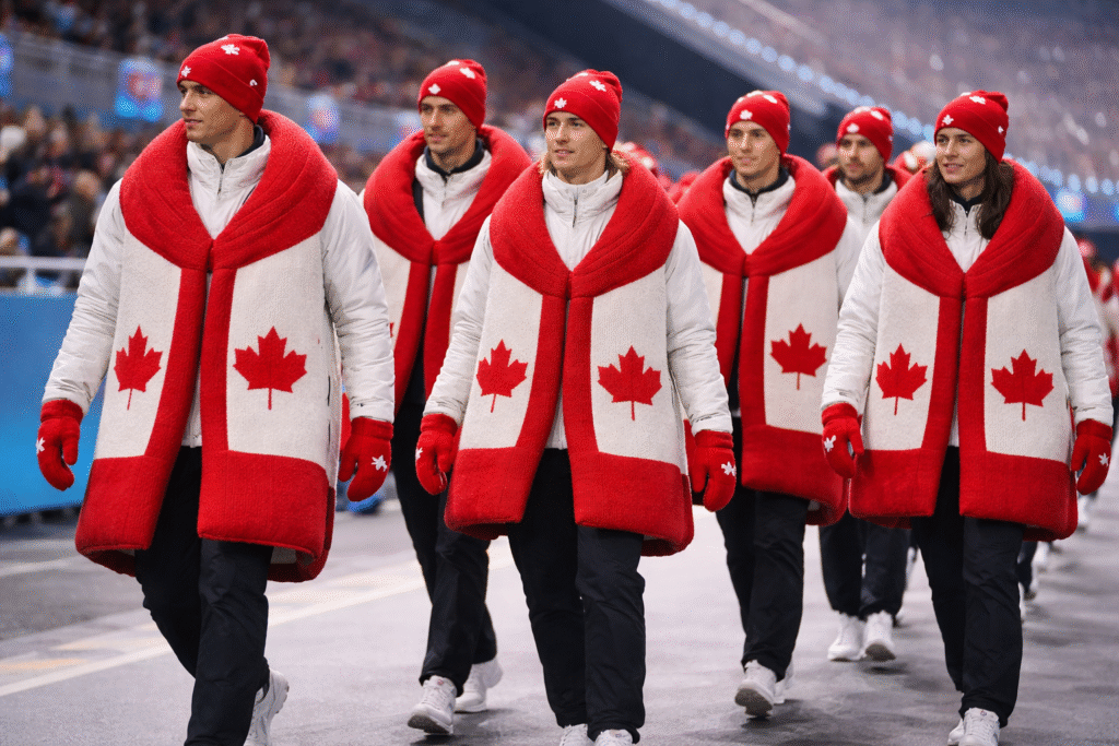 Group of athletes in unusual oversized scarves or vest-like accessories at a stadium concourse, focusing on the unique outfits.