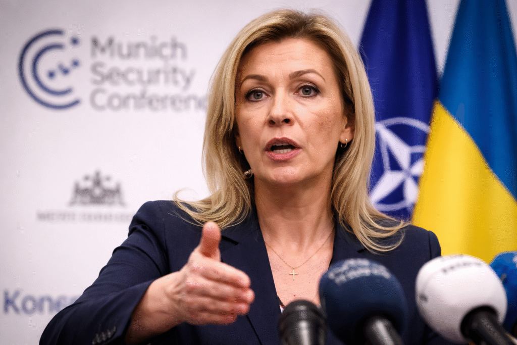 Russian Foreign Ministry spokeswoman speaks at a press briefing with microphones and conference branding visible behind her during an international security event.